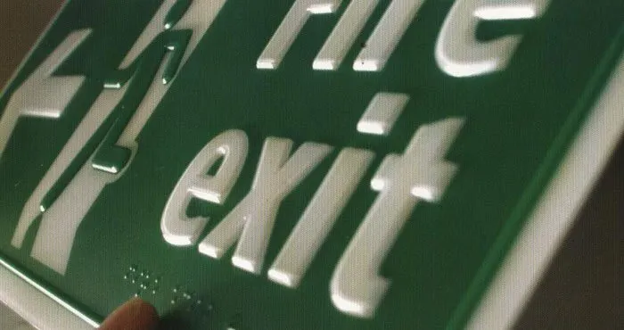 Raised letters and braille on a green plate.