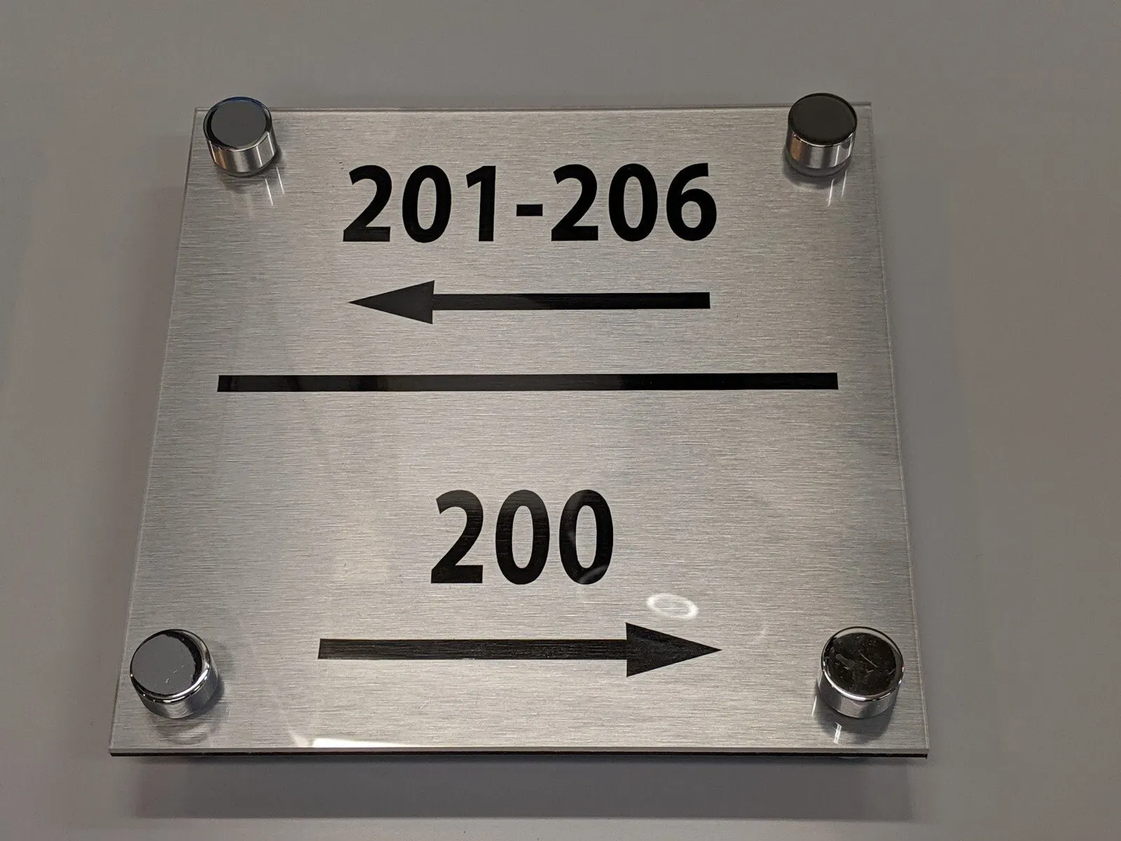 Brushed plate on standoffs with arrows.